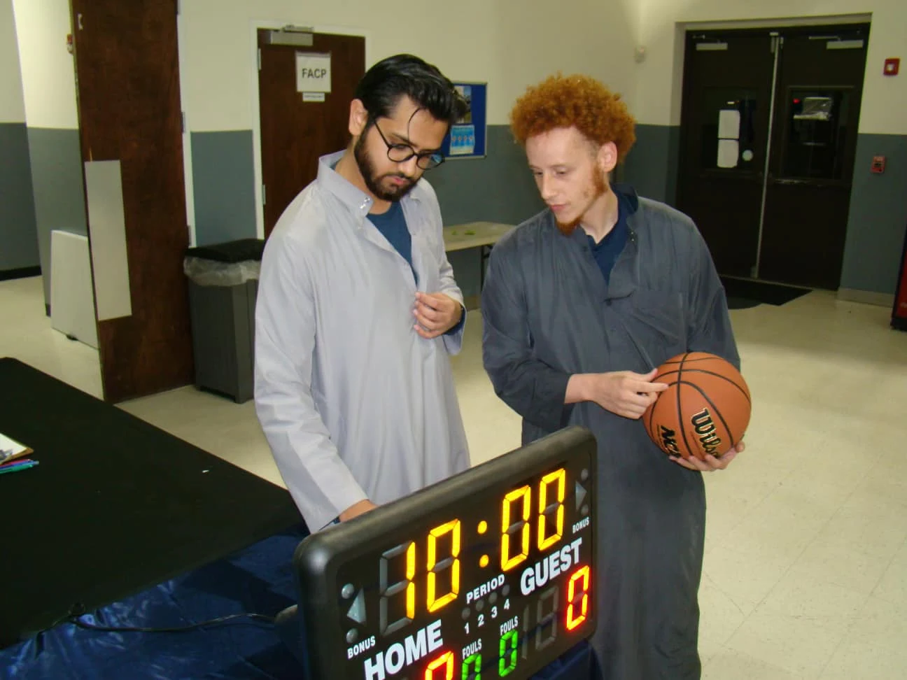 ICC community members beside a basketball scoreboard